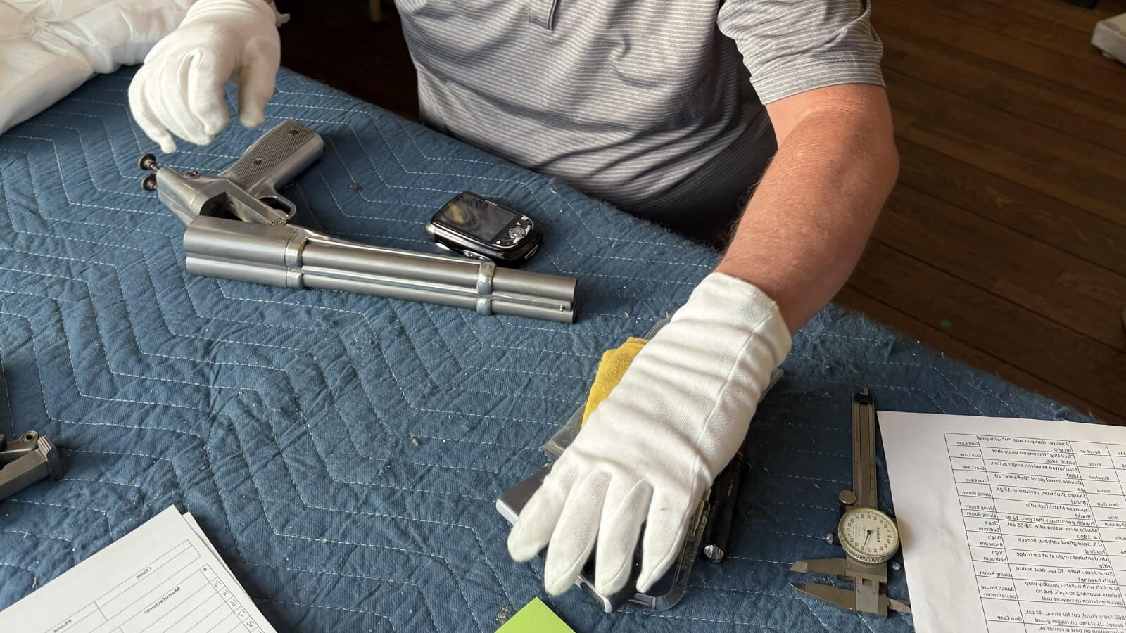 Certified firearm appraiser inspecting a firearm collection during an on-site appraisal.